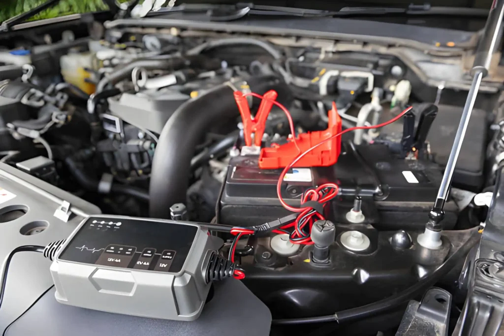 Professional mechanic using red booster clamps to provide a car jump start service in Stretford.