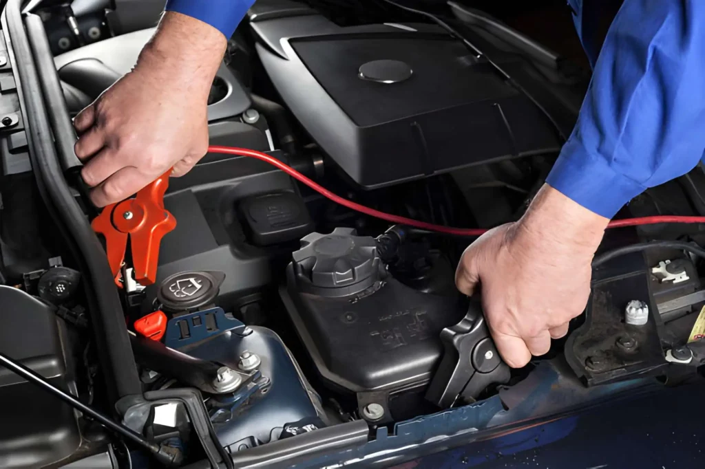 Professional mechanic connecting jumper cables for a car jump start service by Car Jump Start Bros.