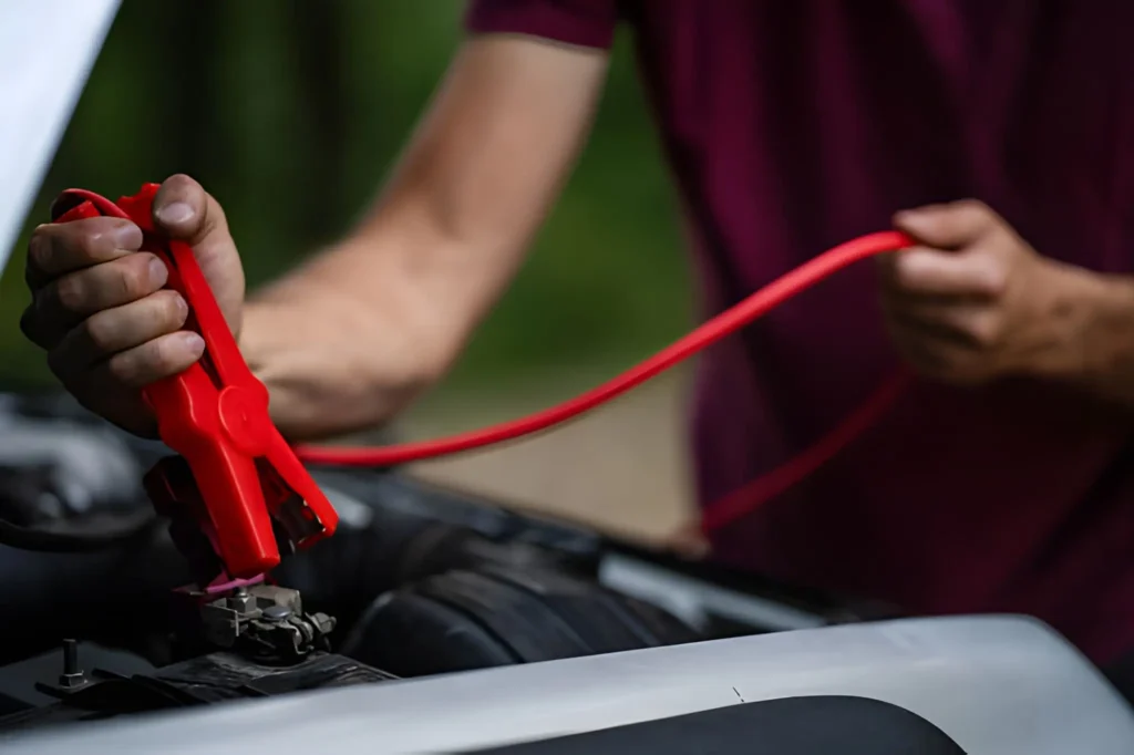 A technician performing a professional jump start on a car battery with red heavy-duty cables in Tyldesley.